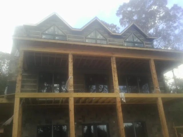 Dormers and porch framing on a large log home under construction — Roof Coating work by our crew in Darden