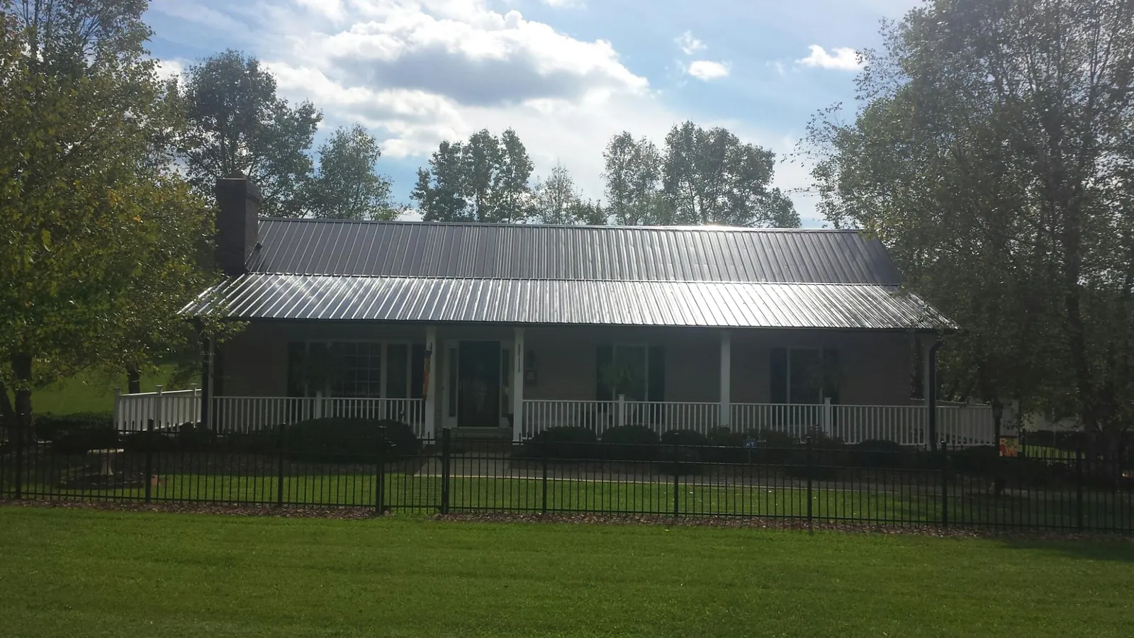 Gray metal roof on a brick ranch with a full width front porch — Gutter Guard Installation work by our crew in Darden