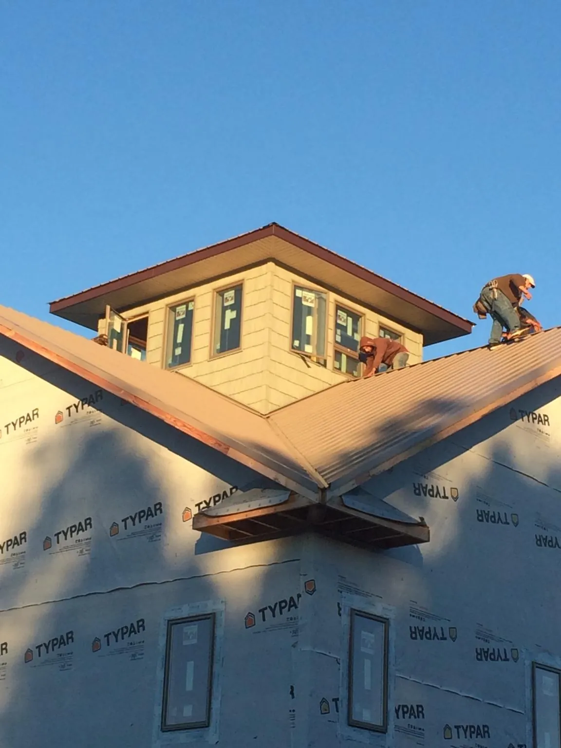 Roofers working around a rooftop cupola on a new metal roof at sunset — Roof Waterproofing in Darden by Roofing Brothers